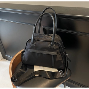 Dettaglio della borsa da viaggio in nylon con finiture in pelle e tracolla su sedia