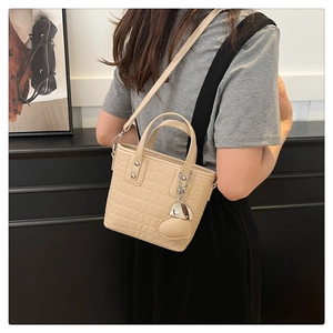 Detailed back view of a beige crocodile textured mini bucket bag with heart pendant charm