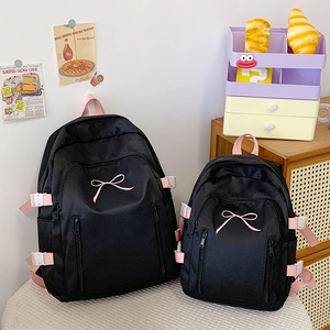 Comparaison détaillée de sacs à dos en nylon noir avec broderie de nœud rose