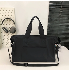 Détail du sac de voyage noir avec doubles poignées et bandoulière réglable amovible