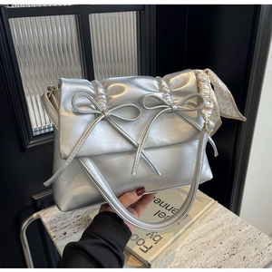 Détail du sac à bandoulière argenté mat avec nœuds et décoration d'écharpe en soie rose