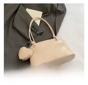 Détail du sac à bandoulière beige avec petit porte-monnaie en cœur sur une veste grise