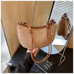 Detail showing handwoven half-moon straw bag with leather trim and knotted strap design