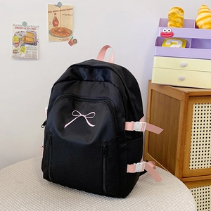 Détail d'un sac à dos noir avec broderie nœud rose et sangles latérales réglables