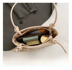 Intérieur d'un sac à bandoulière beige avec pochette zippée et poignée nouée élégante