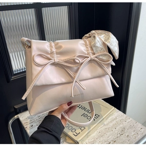 Gros plan sur un sac à bandoulière rose plissé avec nœuds et foulard en soie à cœurs