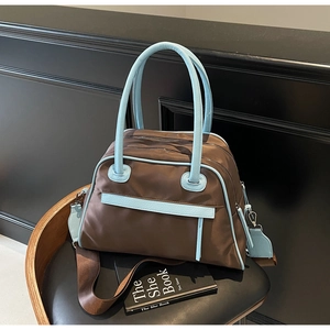 Dettaglio borsa da viaggio con doppia zip in nylon marrone e finiture in pelle azzurra