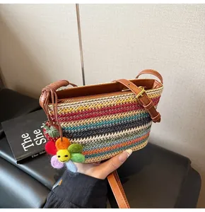 Détail d'un sac en paille tressée arc-en-ciel avec breloques fleurs et bandoulière