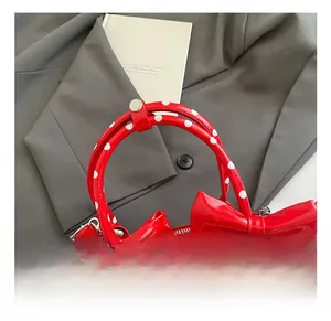 Détail du sac à main rouge à pois en cuir verni avec deux nœuds décoratifs
