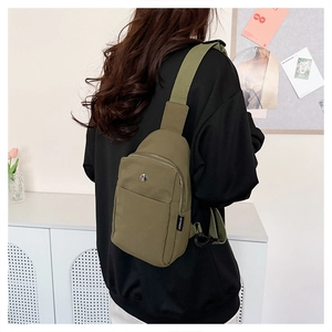 Close-up of a dark green nylon crossbody chest bag with adjustable strap worn on back