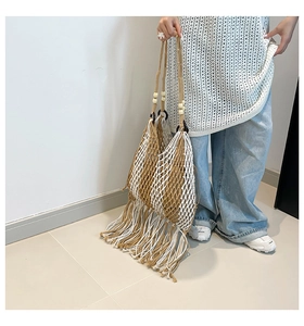 Detail of hand-woven crochet mesh tote bag with long bohemian fringe tassels in khaki and white