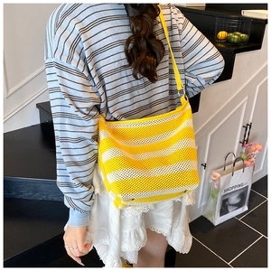 Detail view of large striped mesh tote bag with yellow leather straps on a model