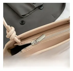 Gros plan détaillé du zip argenté et de la bandoulière nouée d'un sac seau beige chic