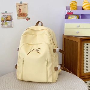Détail d'un sac à dos jaune clair avec broderie nœud et doubles poches zippées devant