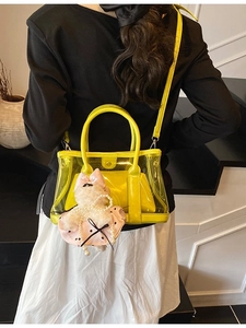 Sac seau jaune translucide avec pochette et charme de chat porté par le mannequin