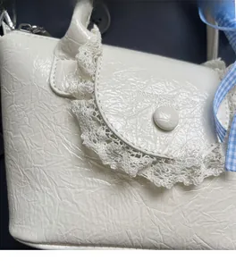 Detailed macro view of the ruffled cream leather texture and delicate white lace trim on the bag