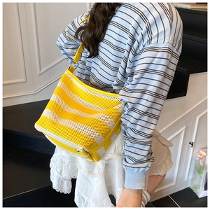 Detail of yellow and white striped woven tote bag with adjustable leather shoulder strap