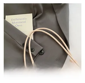 Détail de la poignée en cuir beige avec nœud décoratif sur tissu de costume gris