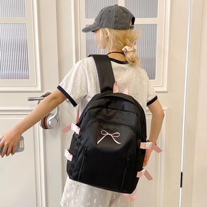 Détail d'un sac à dos en nylon noir avec broderie de nœud rose et sangle réglable