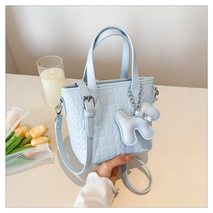 Macro detail of light blue crocodile texture handbag with cute puppy charm and tulip decor