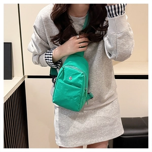 Bright green nylon chest bag worn by a model in a minimalist indoor setting