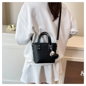 Mini black crocodile embossed crossbody bag with silver heart charm on a model