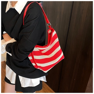Detail of red and white striped knit tote bag with leather strap on model shoulder