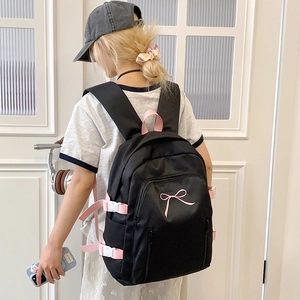 Détail d'un sac à dos en nylon noir avec broderie nœud rose et boucles latérales
