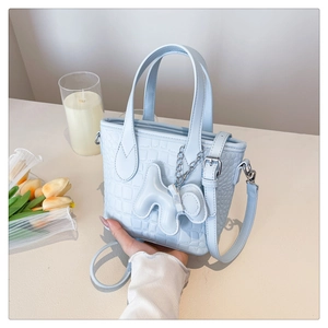 Detail of light blue crocodile pattern bucket bag with a cute charm and tulips