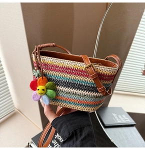 Gros plan d'un sac en paille tissé avec rayures arc-en-ciel et breloque tournesol