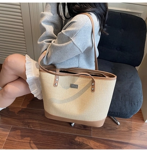 Detail of woven tote bag with brown leather trim shown on model in home setting