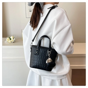 Detail of black crocodile texture handbag with heart charm and silver hardware