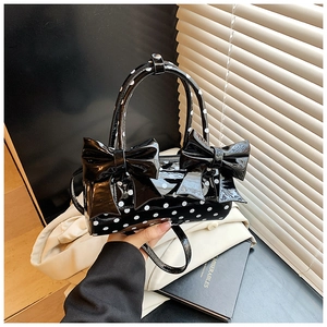 Gros plan d'un sac oreiller noir brillant à pois avec deux grands nœuds en cuir verni