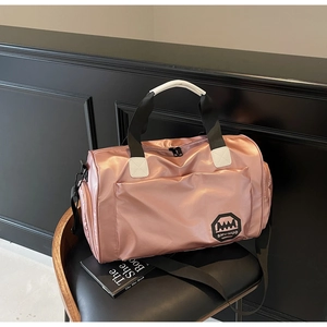 Sac de voyage rose imperméable avec poignées noires et bandoulière sur un tabouret