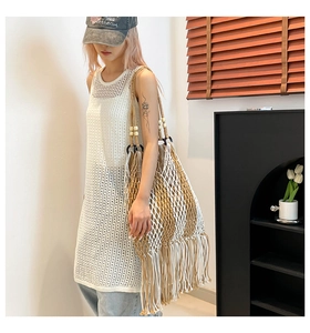 Detail of hand-woven mesh tote bag with khaki and white tassels for beach vacations
