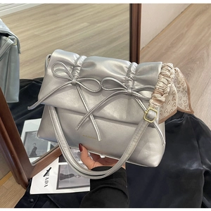 Détail du sac à bandoulière plissé argenté avec nœuds et foulard en soie à cœurs