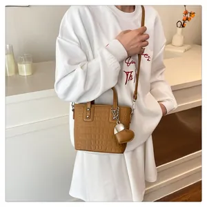 Detail of brown crocodile pattern bucket bag with heart pendant and leather strap