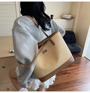 Detail of handwoven straw tote with premium brown leather trim and metallic brand plaque