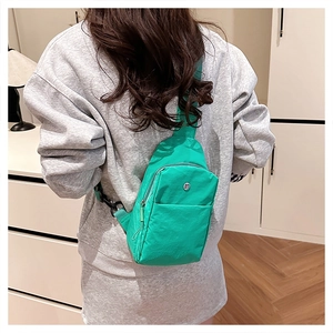 Close-up of bright green nylon crossbody chest bag showing metal logo and front zipper