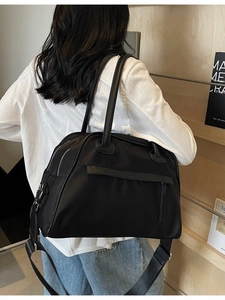 Borsa da viaggio bicolore nera con doppio manico e tracolla larga indossata dal modello