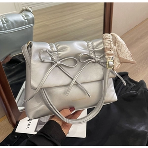 Vue détaillée du sac à main plissé argenté avec nœuds décoratifs et foulard en soie