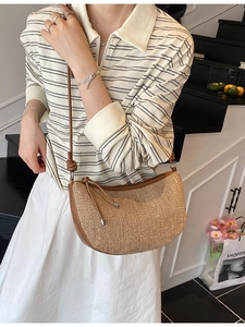 Handwoven straw crescent shoulder bag with brown leather strap and knot detail
