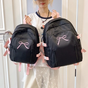 Détail de sacs à dos en nylon noir avec broderie nœud rose en deux tailles pour l'école