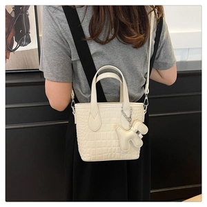 Detail of cream white croc-effect mini tote bag with cute bear charm and removable strap