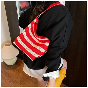 Detail of red and white striped knit tote bag showing soft texture and red leather strap