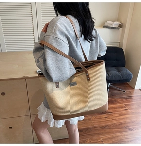 Close-up of woven straw tote bag featuring brown leather straps and a metallic logo