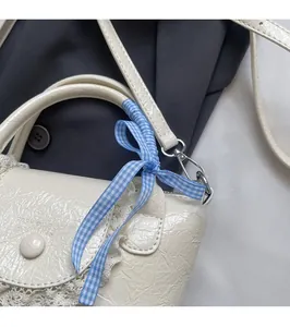Close-up of cream textured leather handbag with lace trim and blue checkered bow detail