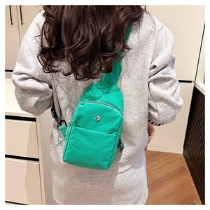 Detail of bright green nylon crossbody chest bag with adjustable strap and metal logo