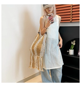 Detail of bohemian knit tote bag with fringe tassels and white hollow crochet dress
