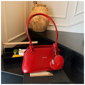 Détail du sac seau en cuir verni rouge avec breloque cœur et logo métallique